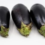 Melanzane ripiene dorate, servite su un piatto con guarnizioni fresche.