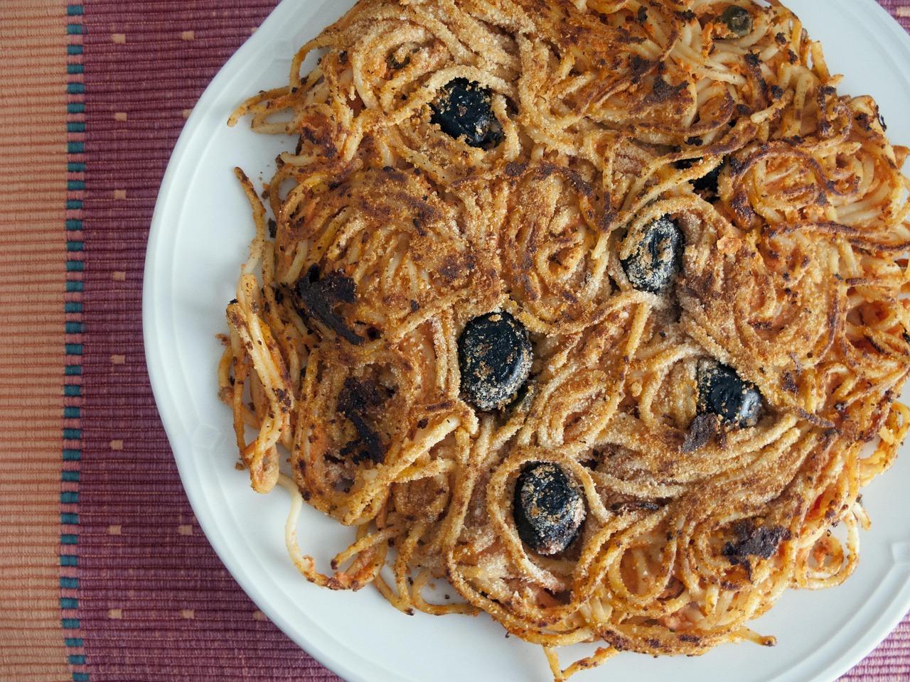 Spaghetti al tonno con olive nere serviti in un piatto rustico, pronti da gustare.