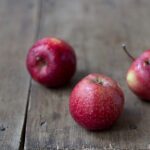 Frittelle di mele dorate su un piatto con zucchero a velo e fettine di mela.