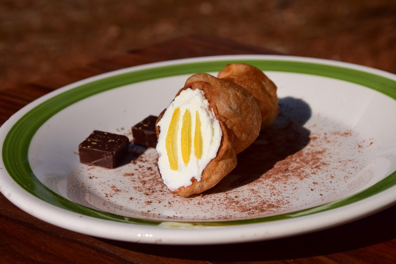 Cannoli siciliani con ripieno di ricotta fresca, decorati con granella di pistacchi e zucchero a velo.