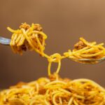Spaghetti al tonno con soffritto di cipolla dorata in primo piano.