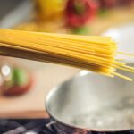 Spaghetti al tonno con pomodorini freschi e olive nere in un piatto cremoso e invitante.