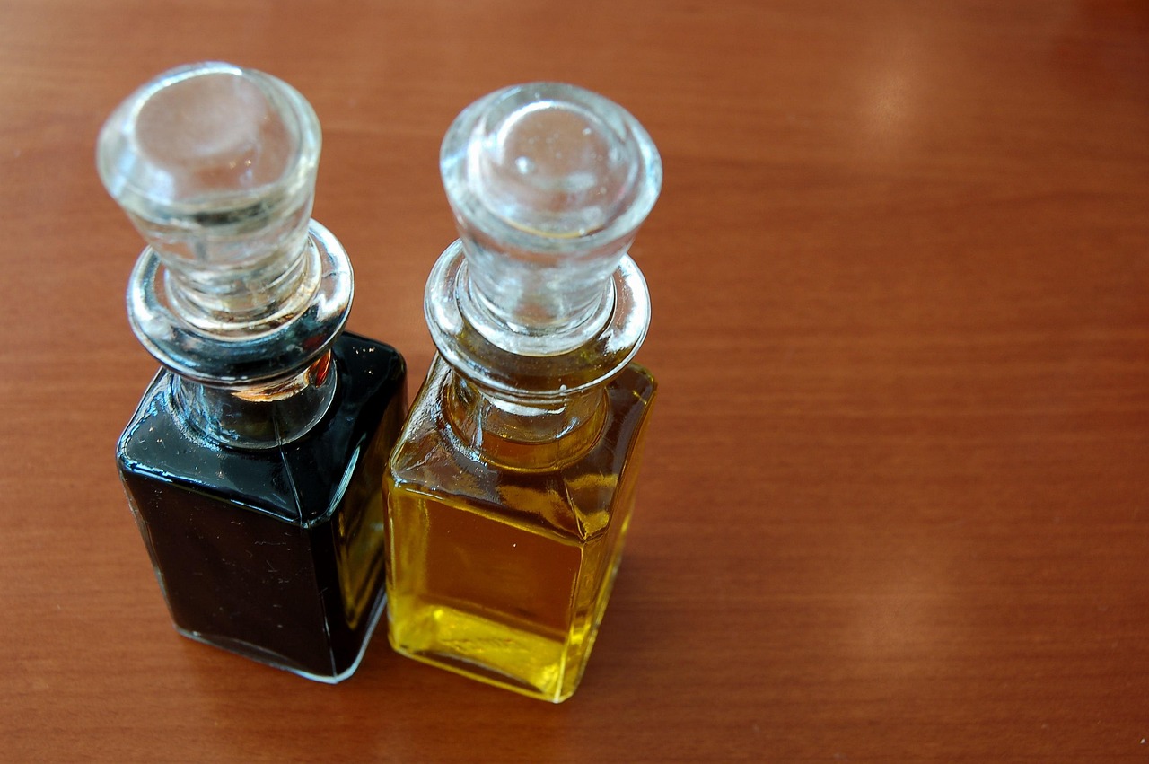 Due bottiglie di olio con etichette diverse, posizionate su un tavolo di legno.