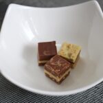 Dado da brodo aperto con ingredienti e additivi in evidenza su sfondo bianco.