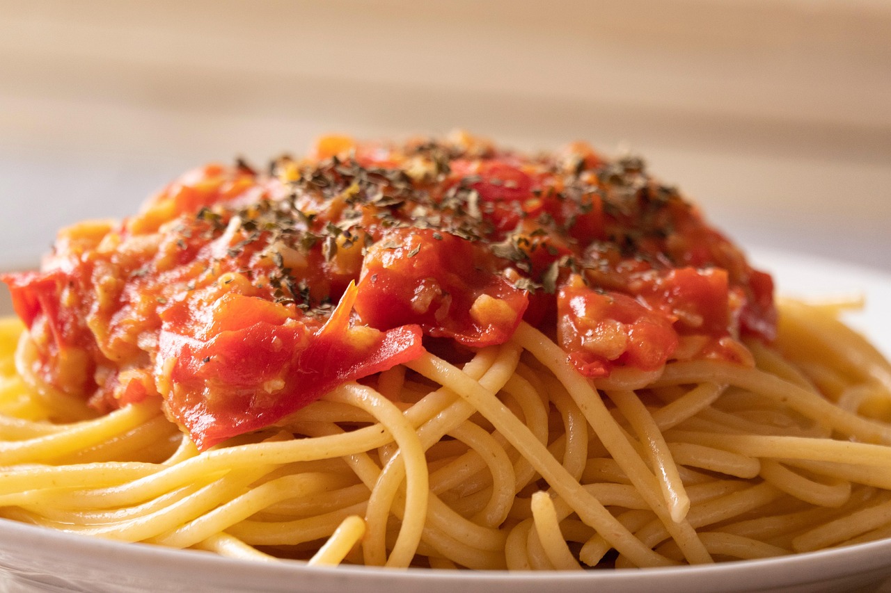 Spaghetti al pomodoro perfetti serviti in un piatto elegante, con basilico fresco e una spolverata di parmigiano.
